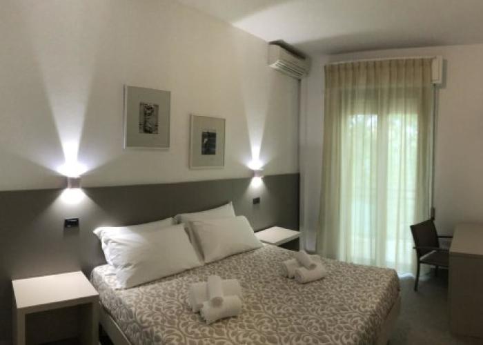 Camera moderna con letto matrimoniale, scrivania, TV e illuminazione soffusa.