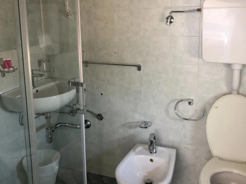 Bagno con doccia, bidet, WC e lavabo su piastrelle chiare.