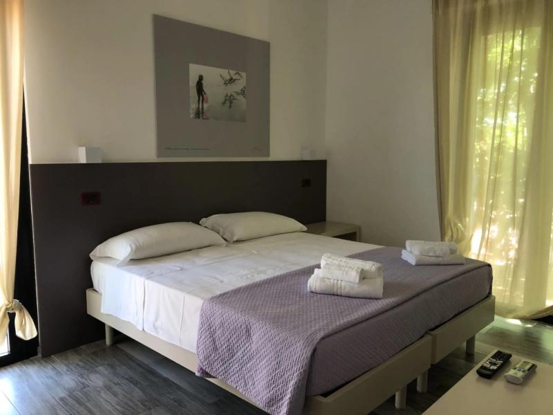 Camera da letto moderna con letto matrimoniale, asciugamani piegati e telecomandi sul tavolo.