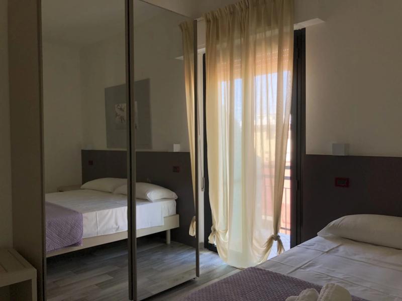 Camera da letto moderna con letto matrimoniale, specchio e tende leggere.