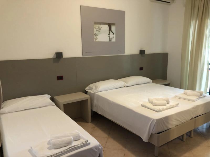 Camera d'albergo moderna con letto matrimoniale e singolo, decorazioni minimaliste.