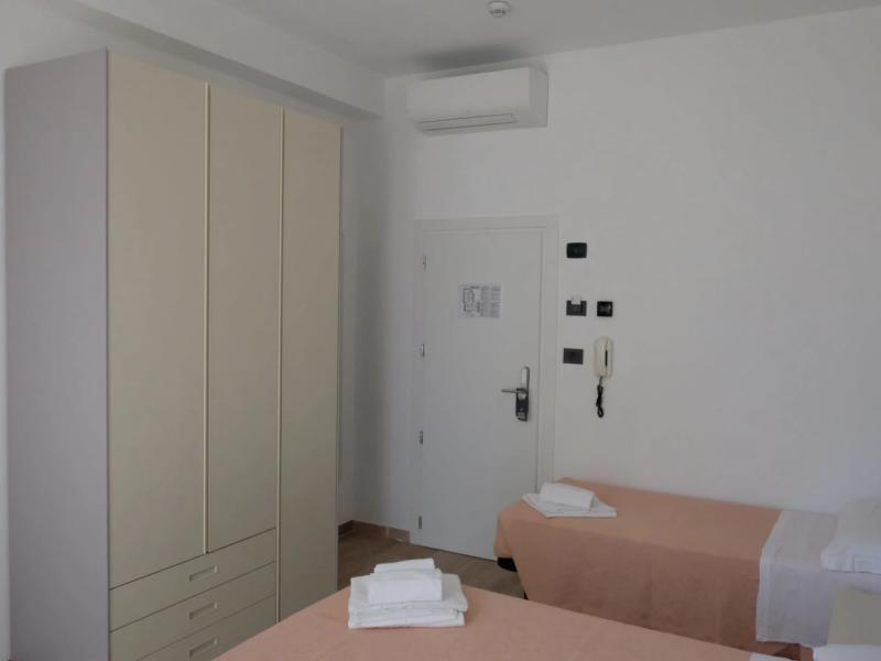 Camera d'albergo con due letti singoli, armadio e aria condizionata.